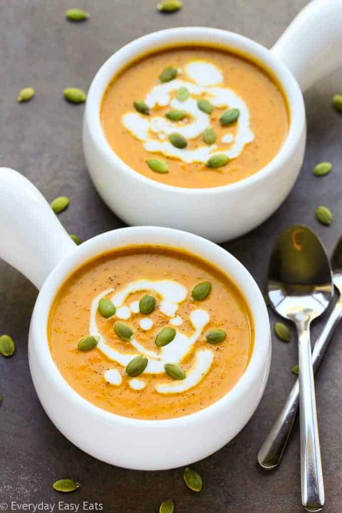 cup of butternut squash soup with coconut milk and pumpkin seeds on top
