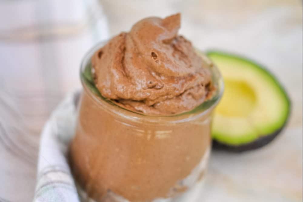 clear dish with chocolate mousse and an avocado beside it